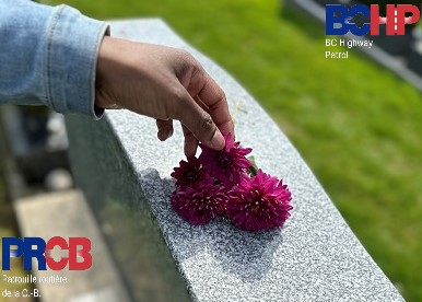 A hand places flowers on a gravestone