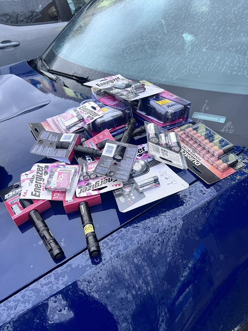 Photo of packages of batteries and flashlights on the hood of a vehicle 